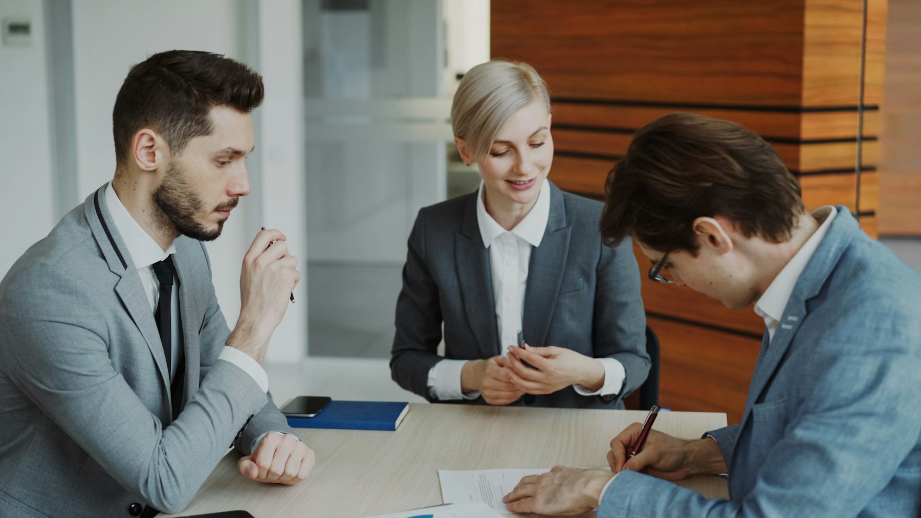 Business people reviewing and signing documents at a table for terms and operating responsibilities.