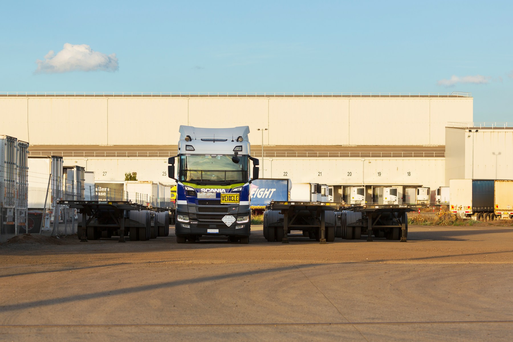Truck and trailers parked in front of a warehouse.